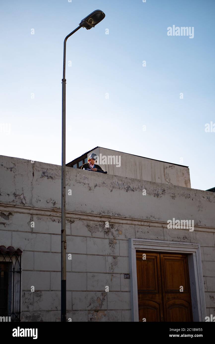 An elderly man standing on the terrace rooftop of the old one store building with a hat on. Stock Photo