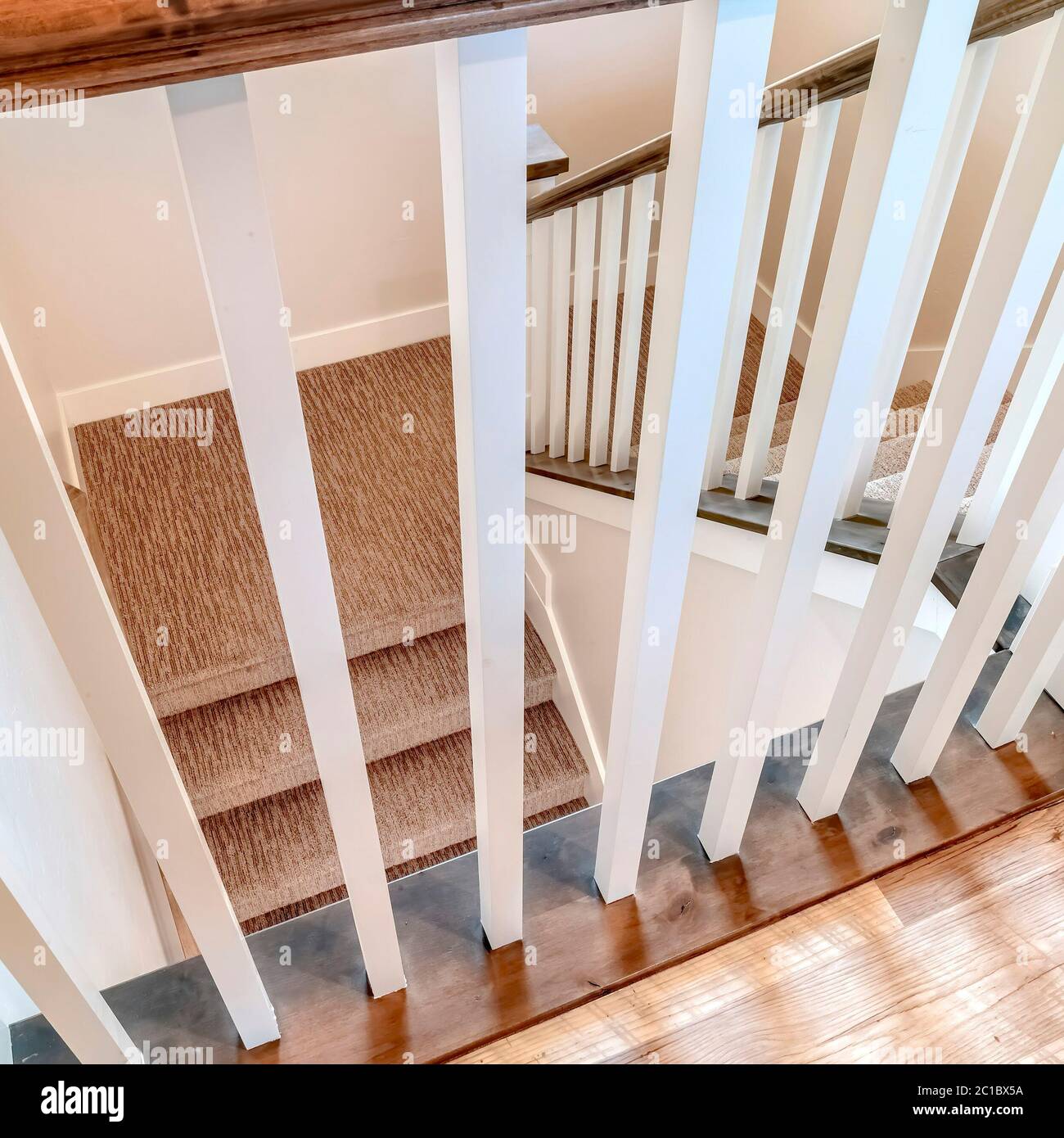 Square White wooden baluster and brown handrail of U shaped staircase