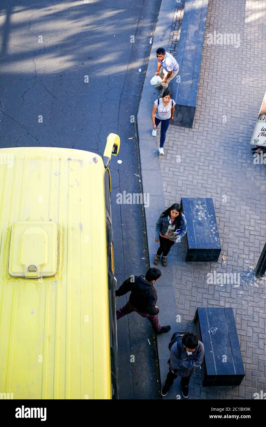 A view of a person jumping off from the Peruvian local bus while other people are waiting to enter, the view seen from the bridge above Stock Photo