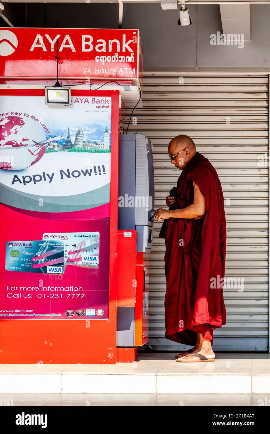 A Buddhist Monk Withdraws Cash From A Cashpoint Machine, Yangon, Myanmar. Stock Photo