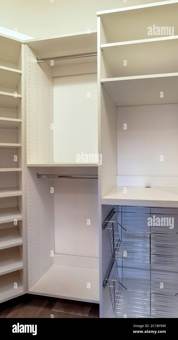 Vertical crop Walk in closet interior with shelves hanging rods drawers ...