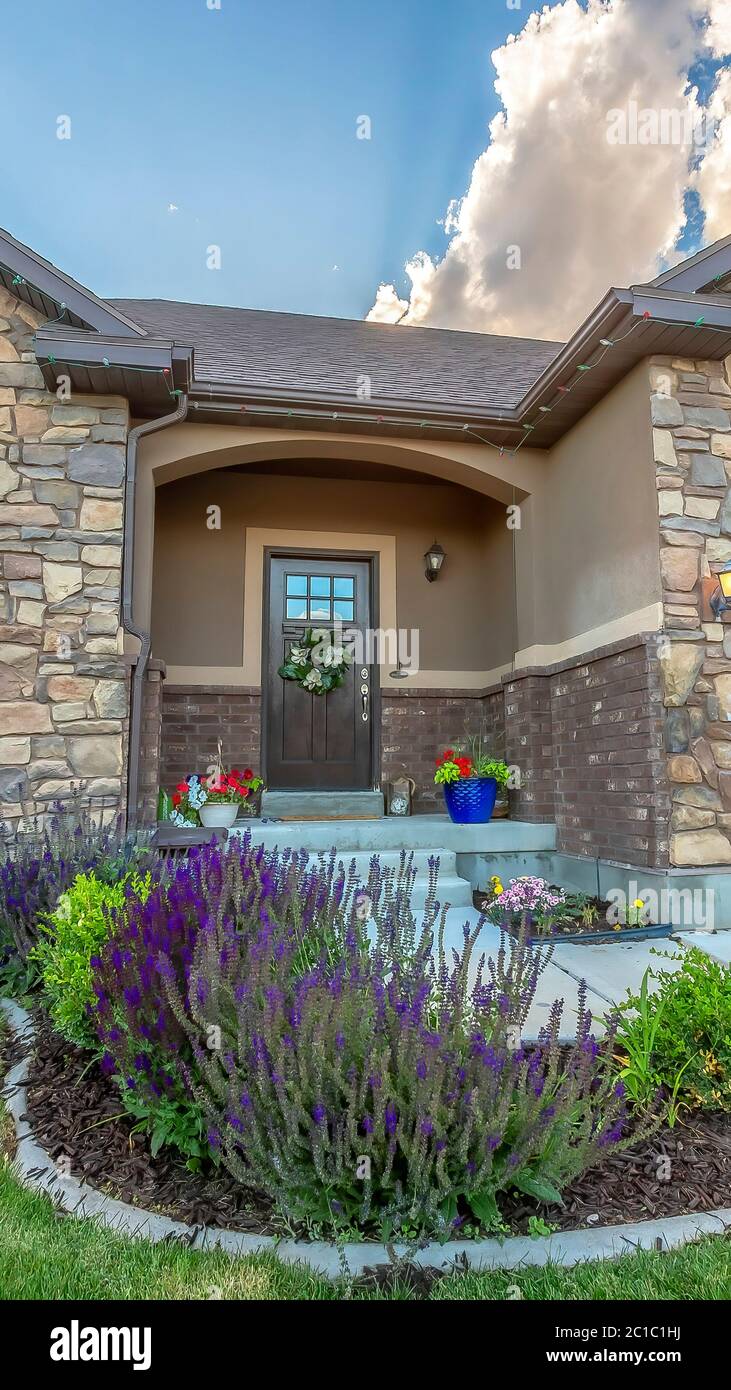 Vertical Facade of home with lush yard in front of stone wall and gable ...