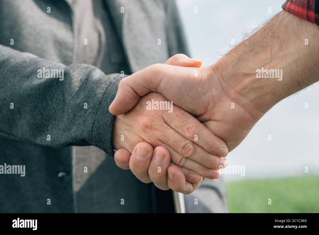 Mortgage loan officer and farmer shaking hands upon reaching an agreement for financial allowance application, banker and farm worker in corn maize cr Stock Photo