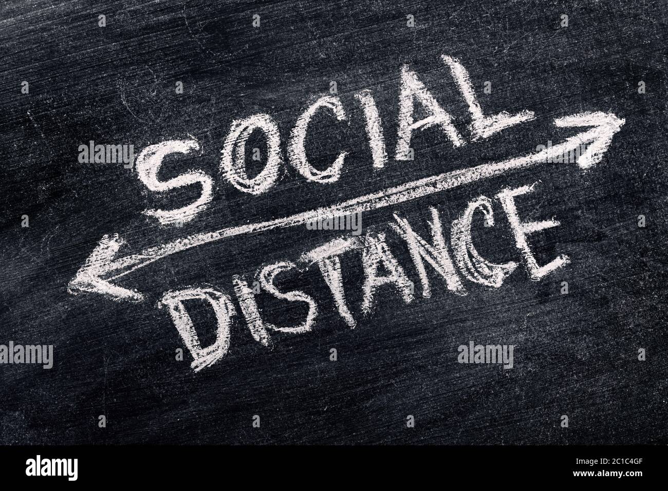 Social distance written in chalk on blackboard, conceptual image referring to distance between different society groups Stock Photo