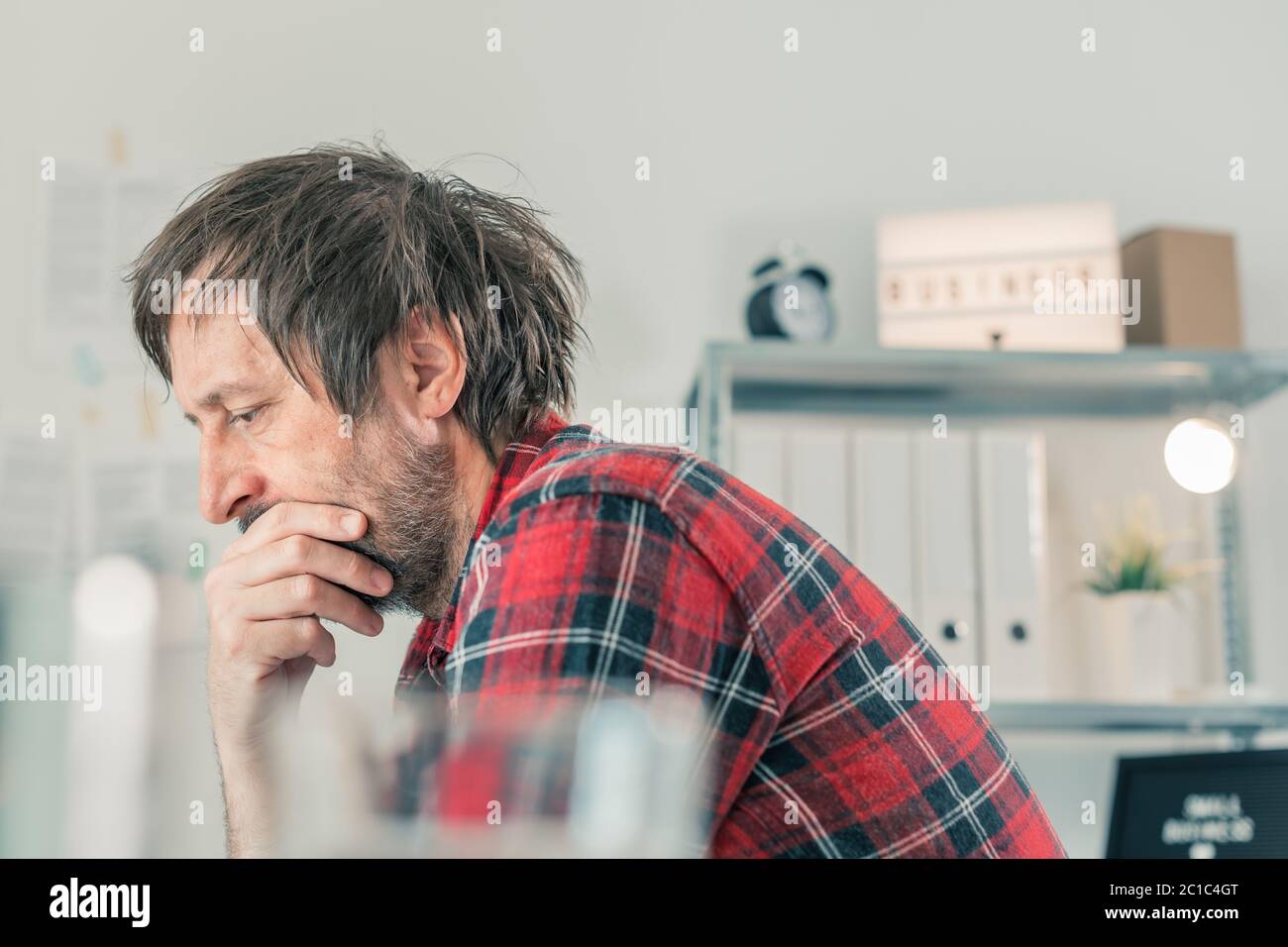 Troubled freelancer thinking in home office interior, selective focus Stock Photo