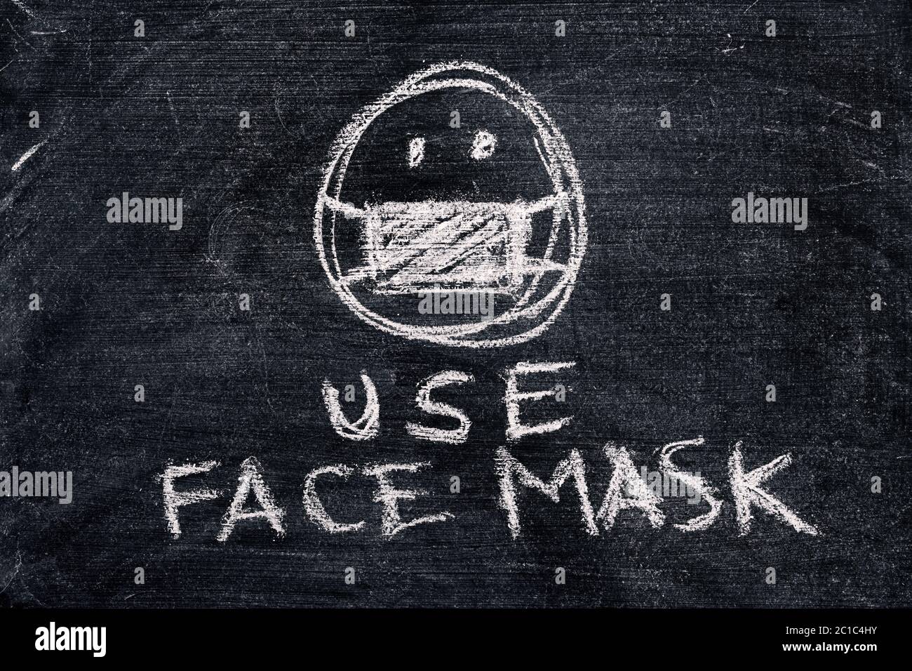 Use face mask, simple chalk drawing on dirty blackboard Stock Photo