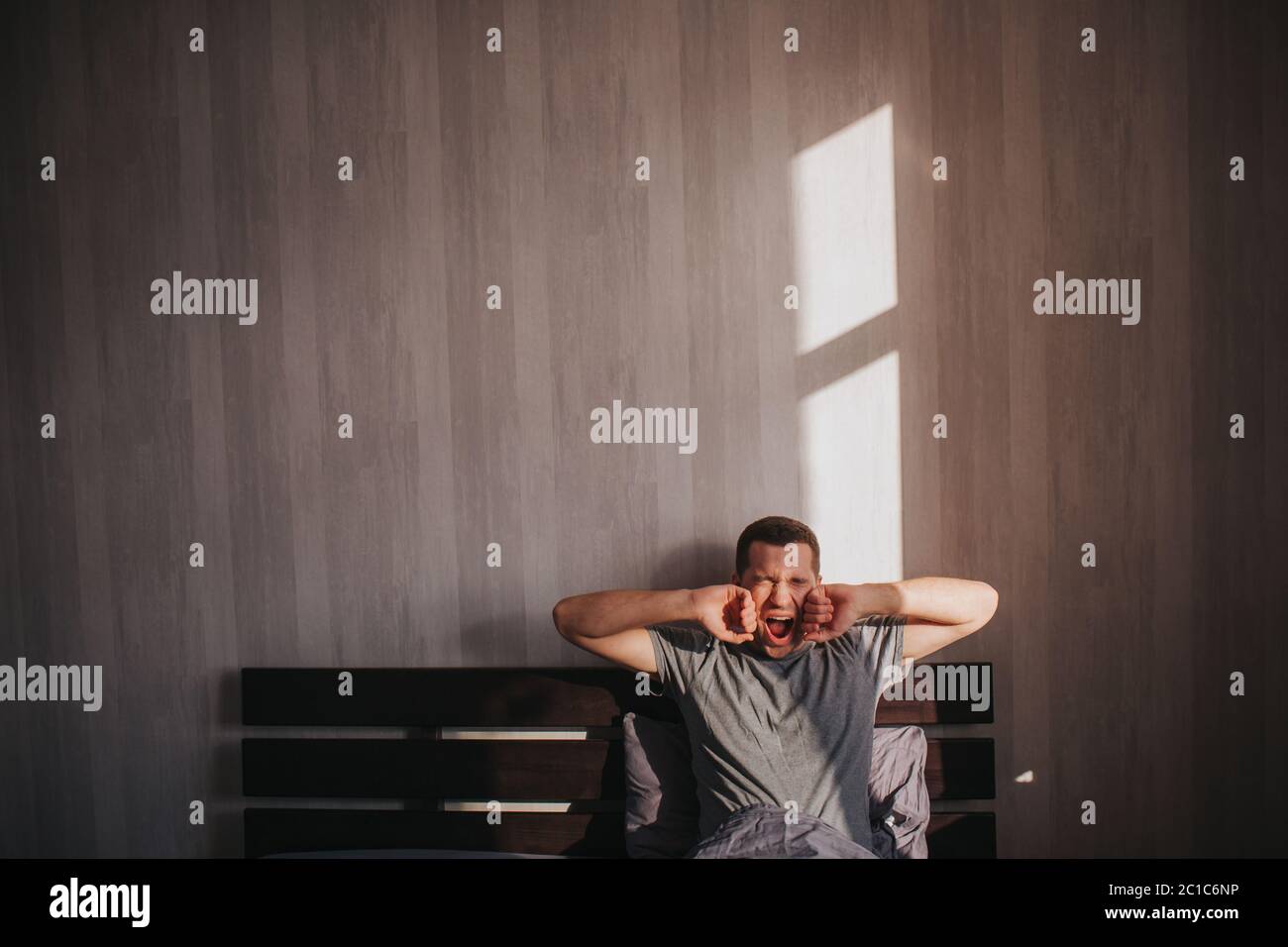 A man in his bed in the morning. He is stretching. Great start to the day. Stock Photo