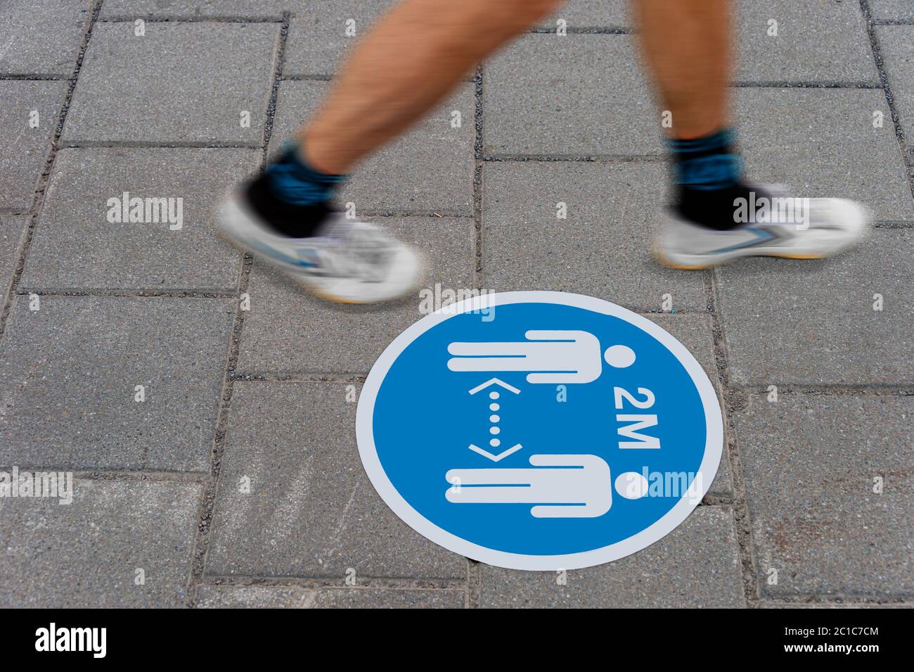 Sign printed on ground informing people to keep a 2 meter distance from each other during Covid-19 pandemic. Stock Photo