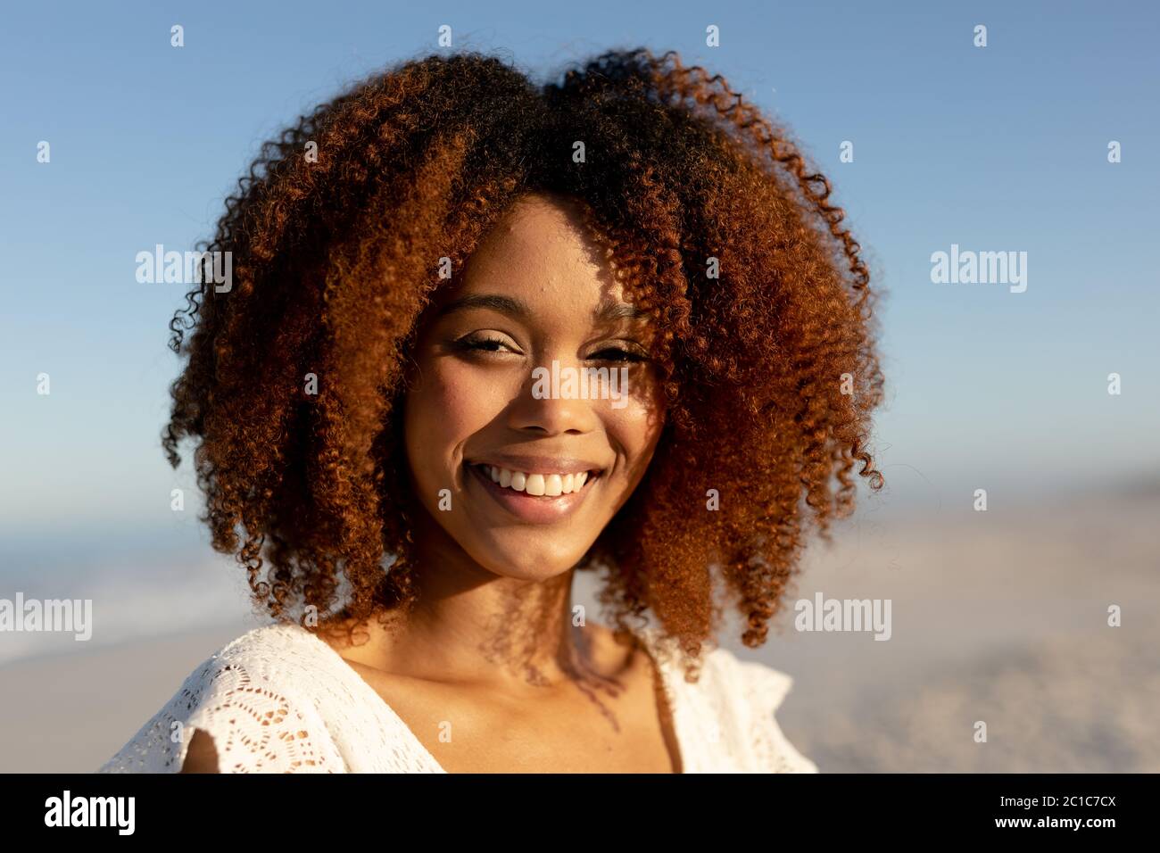 Mixed race woman enjoying free time on beach on a sunny day and staring into the camera Stock Photo
