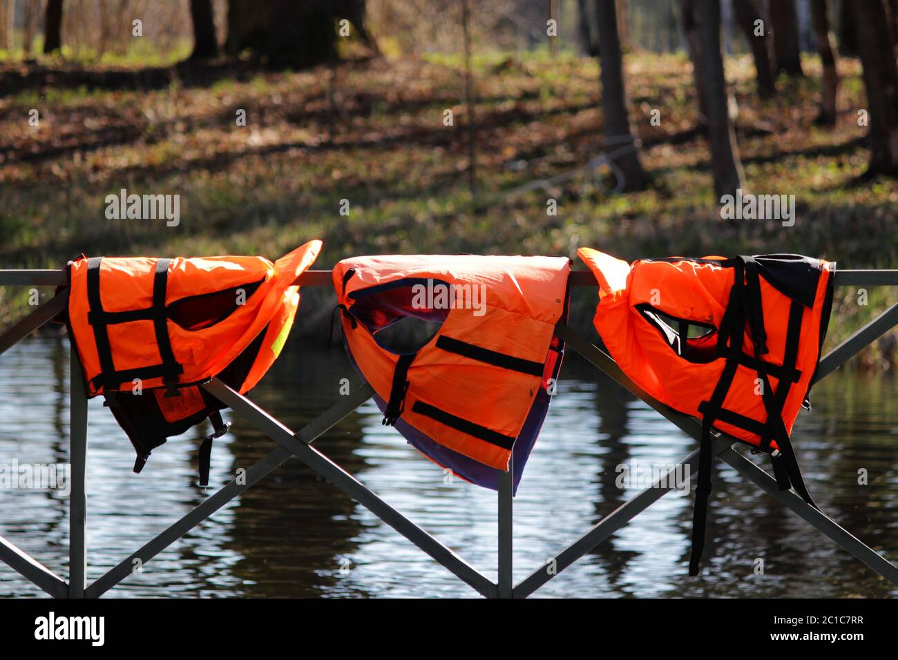 three orange lifejackets hang on the railing near the pier at the boat station. Gatchina, Russia. Stock Photo