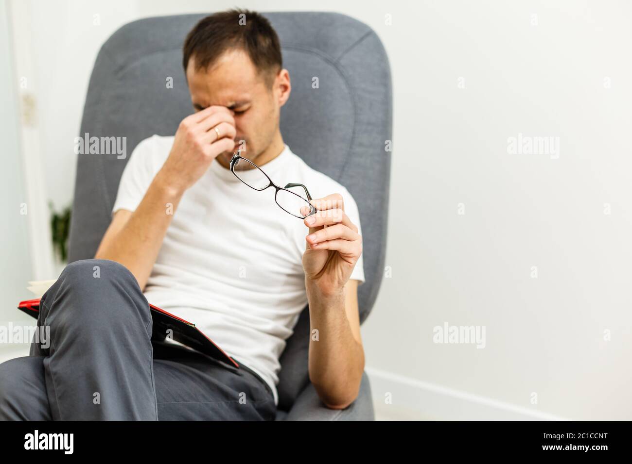 Man with tired eyes after long work holding his eyeglasses Stock Photo