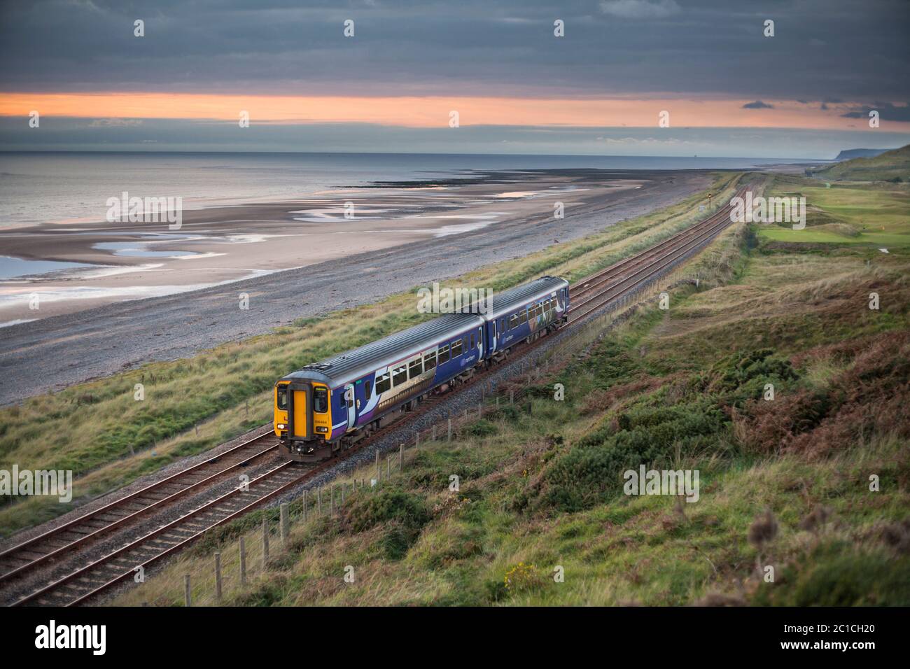 Northern Rail class 156 sprinter train passing Seascale beach on the scenic Cumbrian coast railway line. Stock Photo