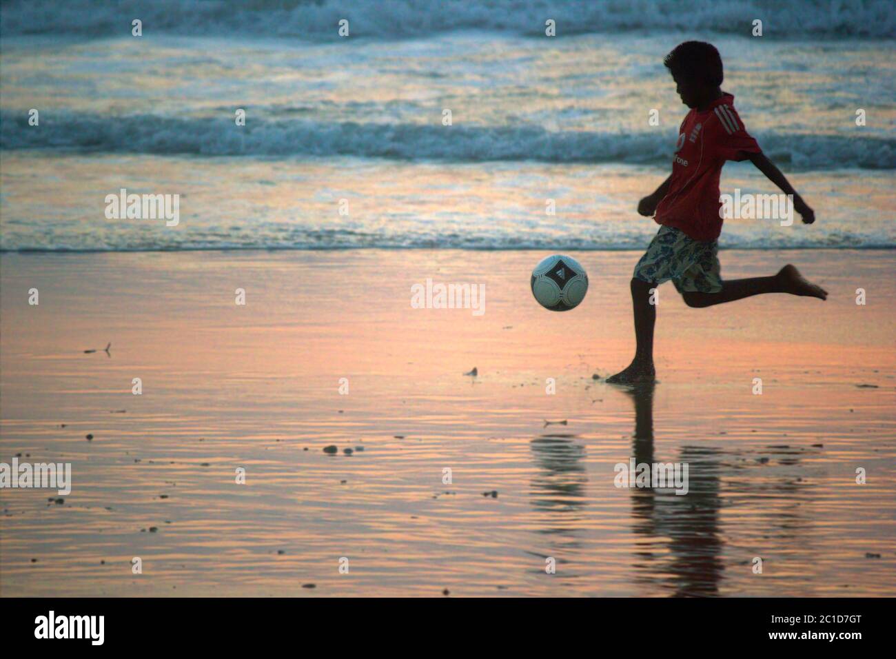 Kid playing with football in Goa beach (selective focus) Stock Photo