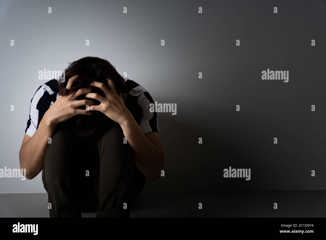 sad man hug her knee and cry sitting alone in a dark room. Depression ...