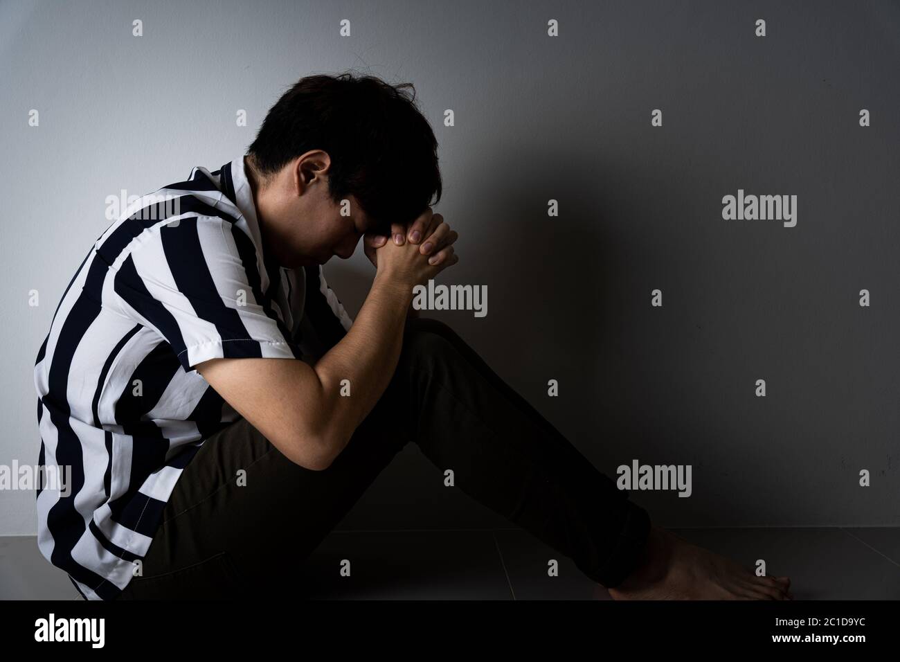sad man hug her knee and cry sitting alone in a dark room. Depression ...