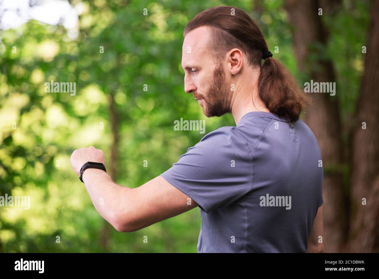 Athlete sport man runner is looking at smart watch bracelet at park, healthy lifestyle, healthcare, activity concept Stock Photo