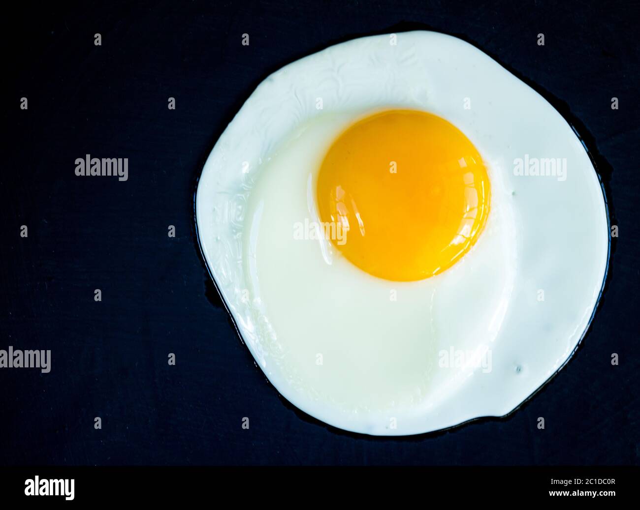 Fried egg isolated on rustic black background Stock Photo