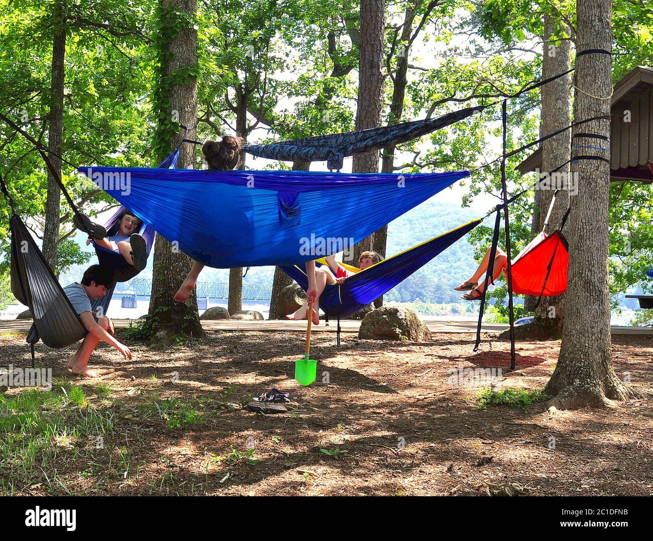 Cartersville, GA-circa May 18, 2019:  Young boys and girls laughing and playing together having fun swinging in hammocks by the lake on Red Top Mounta Stock Photo