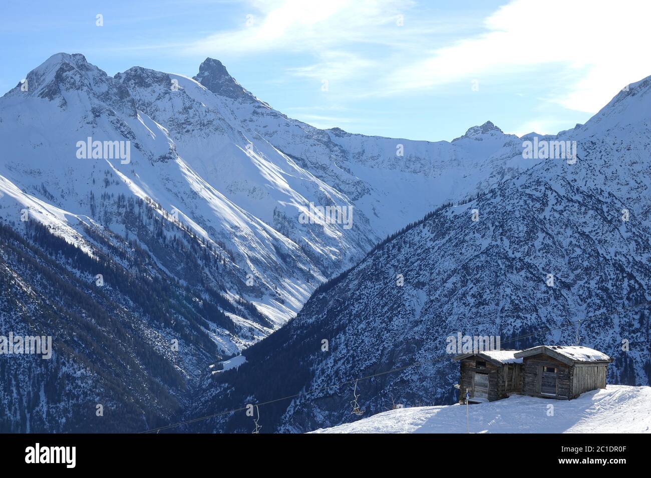 Chairlift at two wooden huts near the snow-capped mountains in Tyrol. Stock Photo
