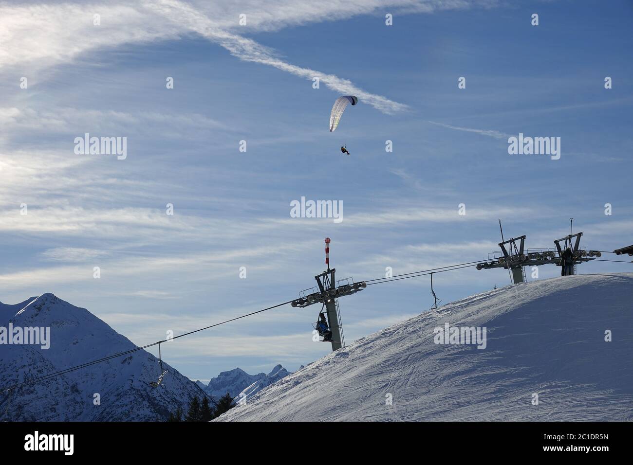 Paragliders and skiers at the chairlift in the snow-covered mountains of the Lech Valley in Austria / Tyrol. Stock Photo