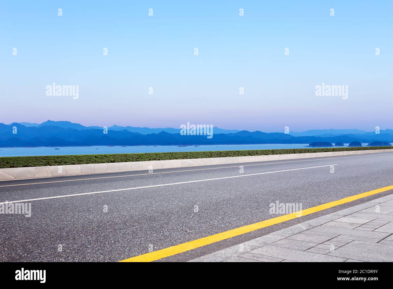 asphalt road and blue sky with white clouds by the lake Stock Photo - Alamy