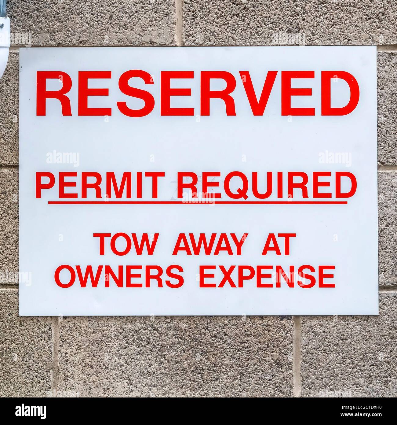 Square frame Reserved sign and downspout against wall of building and corrugated garage door Stock Photo
