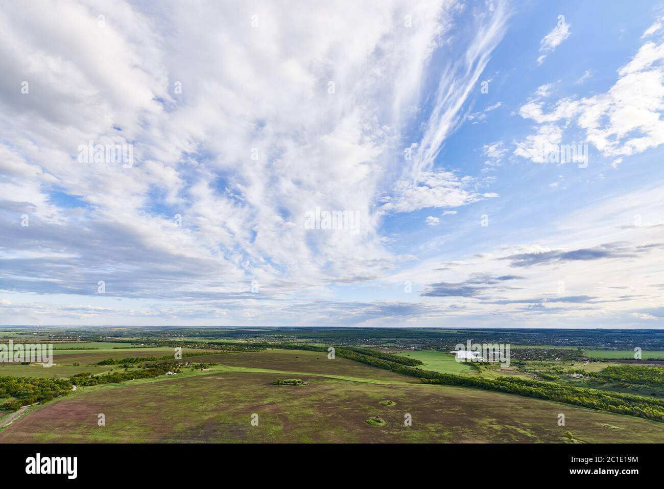 Aerial view of farmland under a blue sky with clouds in the sunlight ...
