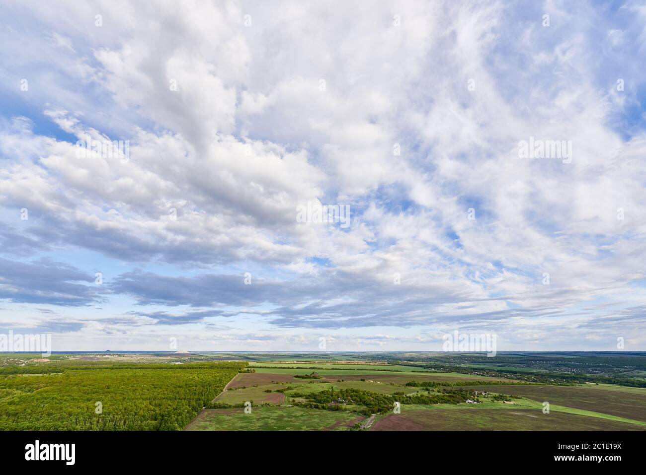 Aerial view of green fields and trees under a blue sky with clouds in ...