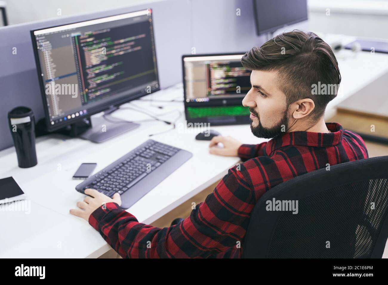 Software developer working on computer in IT office, sitting at desk and coding, working on a project in software development company or technology Stock Photo