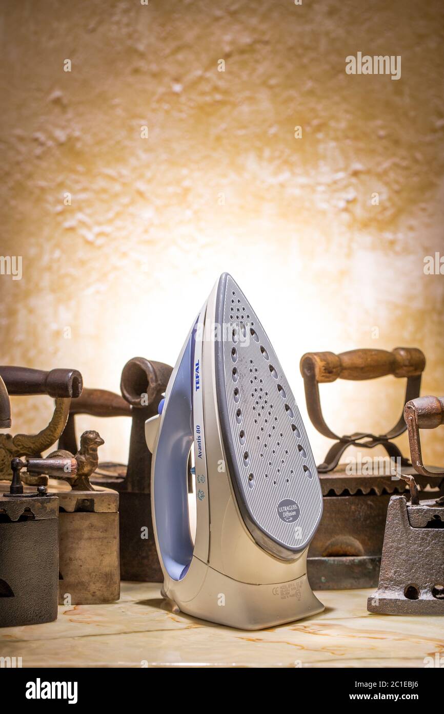 Cocept of old and new technologies. Photo of old and modern irons on the vintage stucco background. Stock Photo