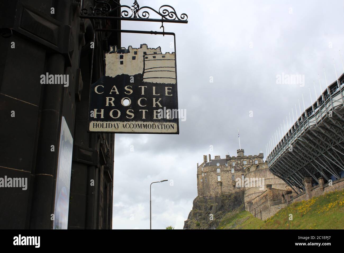 Edinburgh, Scotland - 25 July 2015: Hanging sign of Castle Rock Hostel with Edinburgh Castle in the background on a cloudy day. Stock Photo
