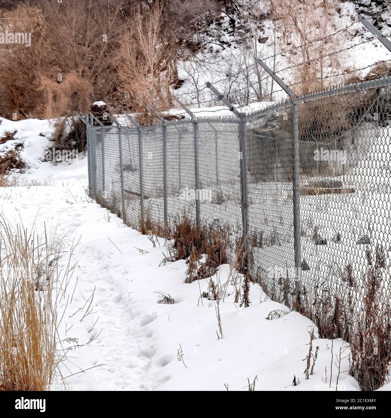 Square frame Chain link fence with barbed wires on snow covered hill