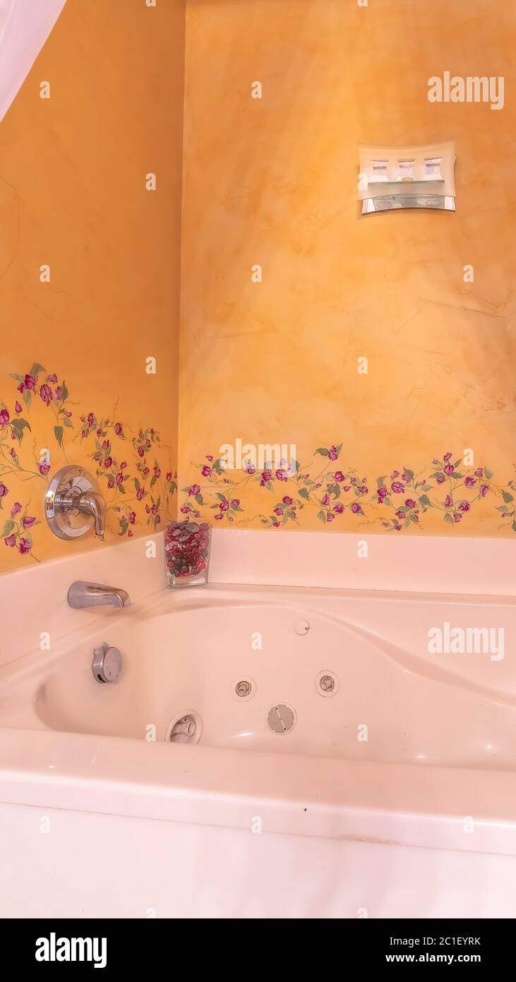 Vertical frame Built in white jacuzzi tub inside a bathroom with flower ...
