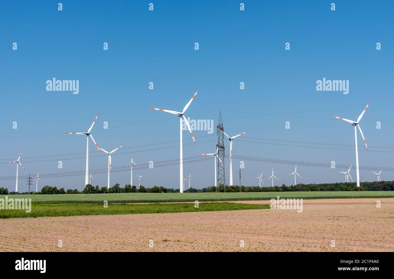 Overhead power lines and modern wind turbines in the fields in Germany Stock Photo