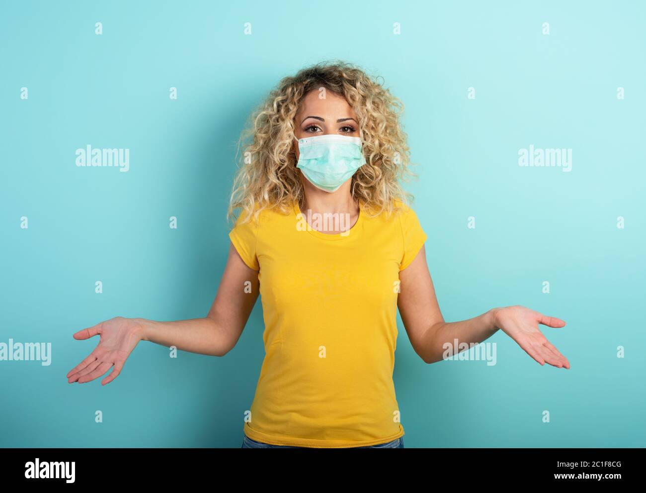 Blonde girl has doubt about covid19 corona virus. Cyan background Stock Photo