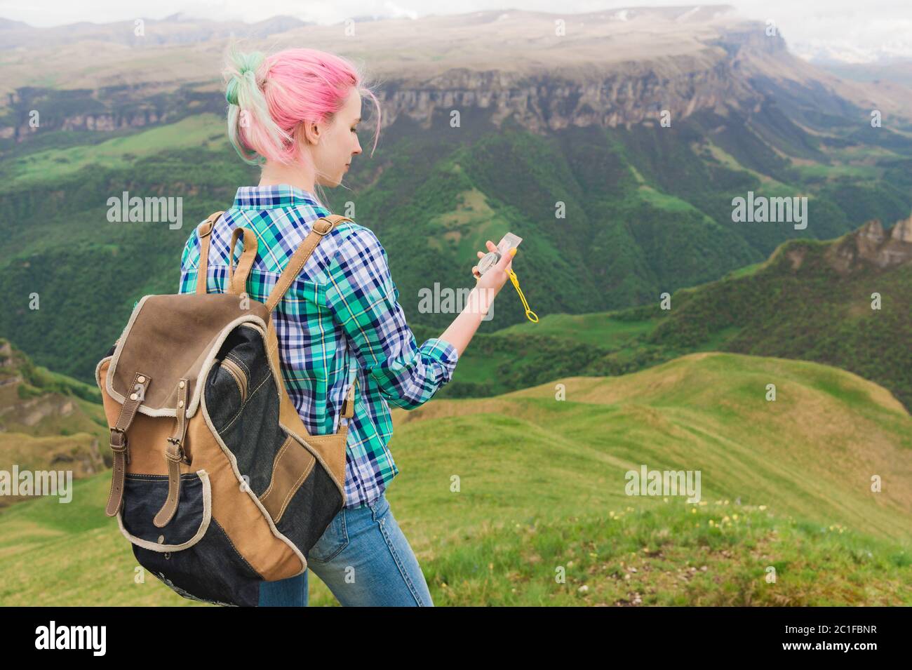 A hipster girl traveled with a blogger in a plaid shirt and with multi-colored hair using a compass in the background in the bac Stock Photo