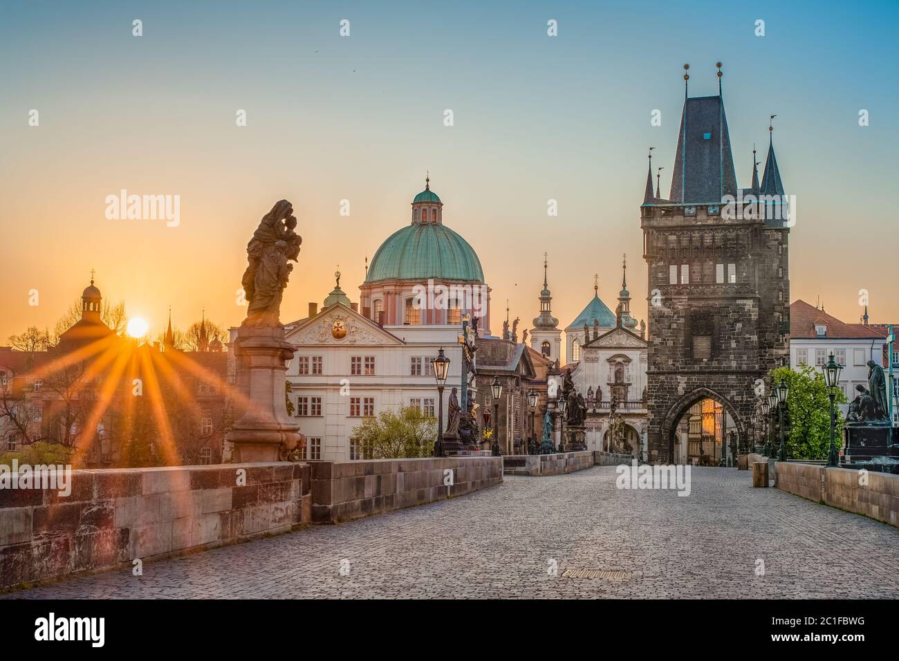 Sun rays filling the scene with colors during sunrise on empty deserted Charles bridge in Prague, Czech Republic --- NIKON D7500 & Sigma 35.0 mm A f/1 Stock Photo