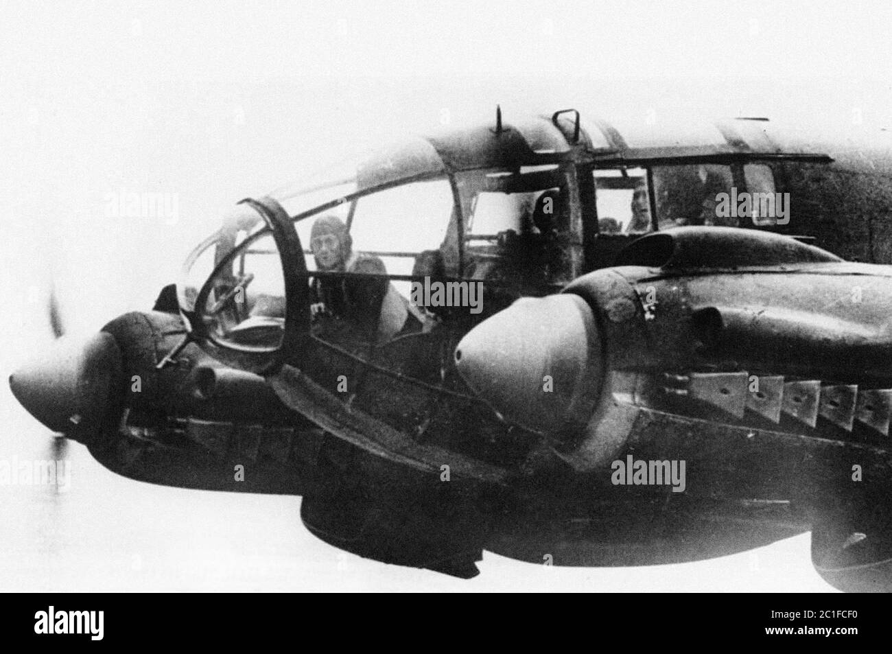 A forward machine gunner sits at his battle position in the nose of a German Heinkel He 111 bomber, while en route to England in November of 1940. Stock Photo