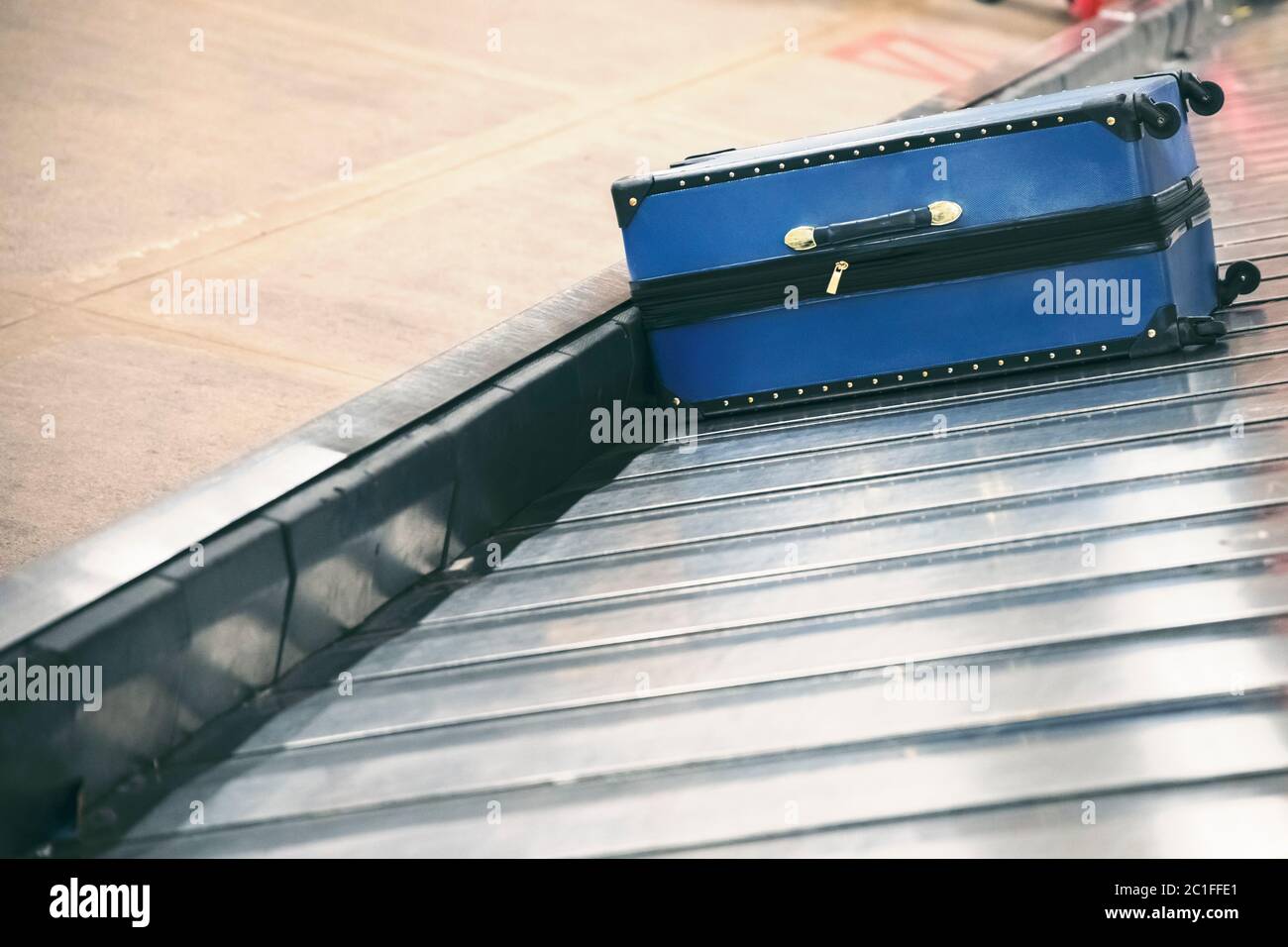 Suitcase on luggage conveyor belt at baggage claim area at airport terminal Stock Photo
