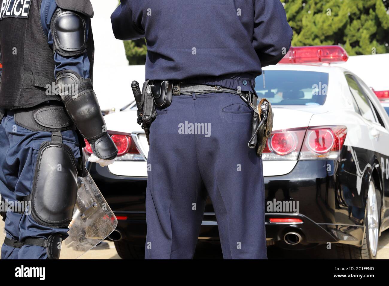 Back view of Japanese police officers with patrol car Stock Photo