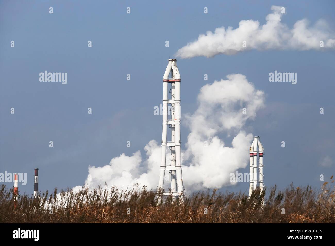 Industrial smokestack with smoke against a blue sky Stock Photo