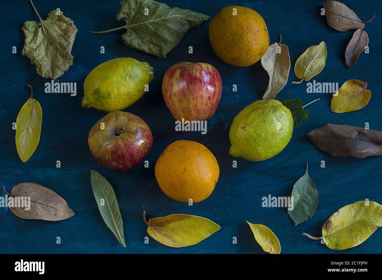 Some oranges, lemons, apples and leafs on a blue background Stock Photo