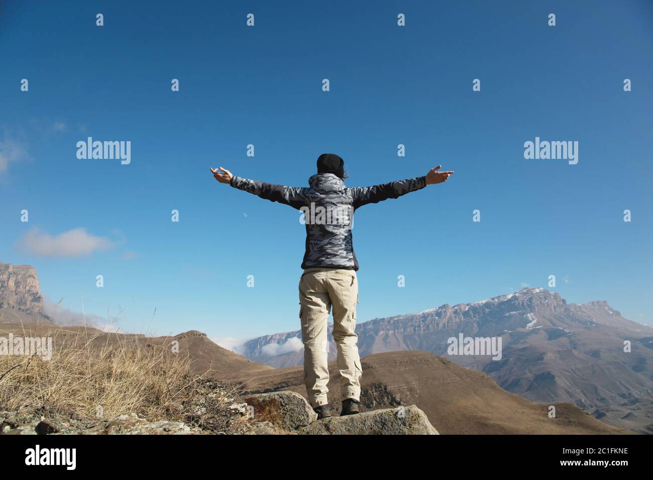 an applause of a young woman backpacker on top of a sprawling upward mountain peak. Freedom and victory against the background o Stock Photo