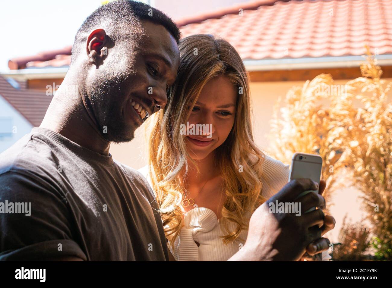 Young woman and man looking at phone together. Medium shot. Side view. Stock Photo