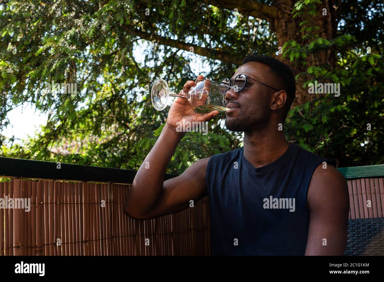 Young black man drinking wine seated outdoors. Medium shit. Side view. Stock Photo