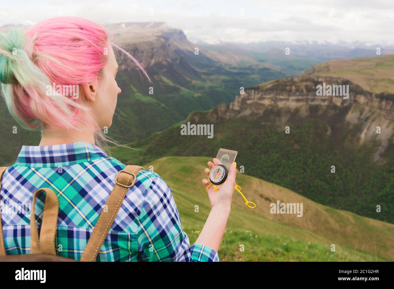 A hipster girl traveled with a blogger in a plaid shirt and with multi-colored hair using a compass in the background in the bac Stock Photo