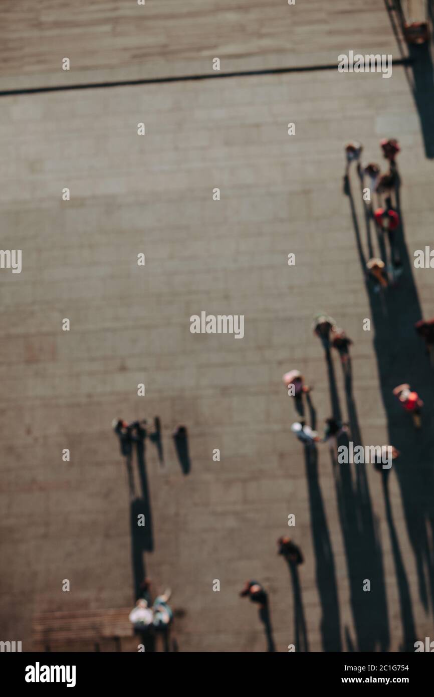 Overhead view of blurred pedestrians walking below, casting long shadows Stock Photo