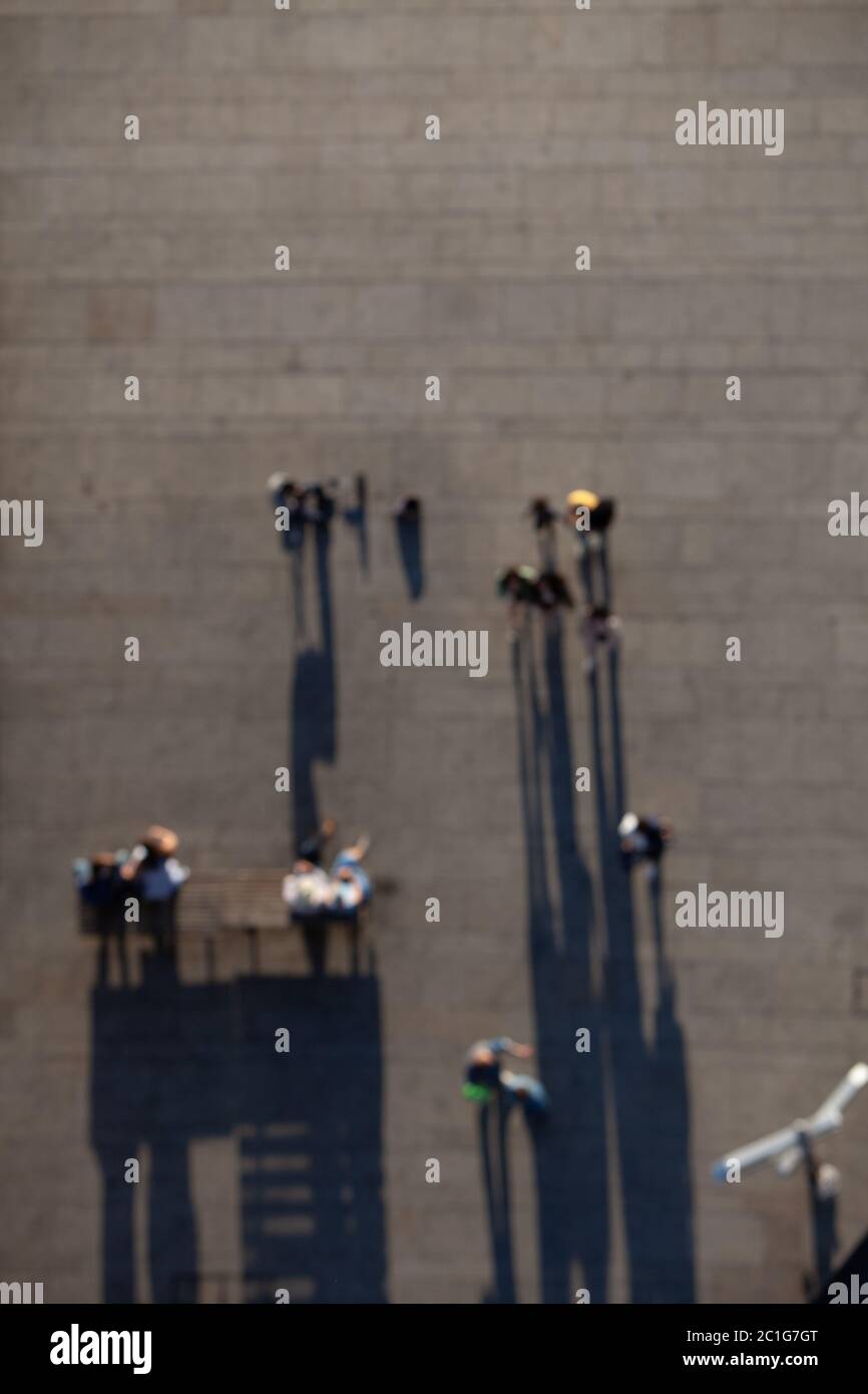 Overhead view of blurred pedestrians walking below, casting long shadows Stock Photo