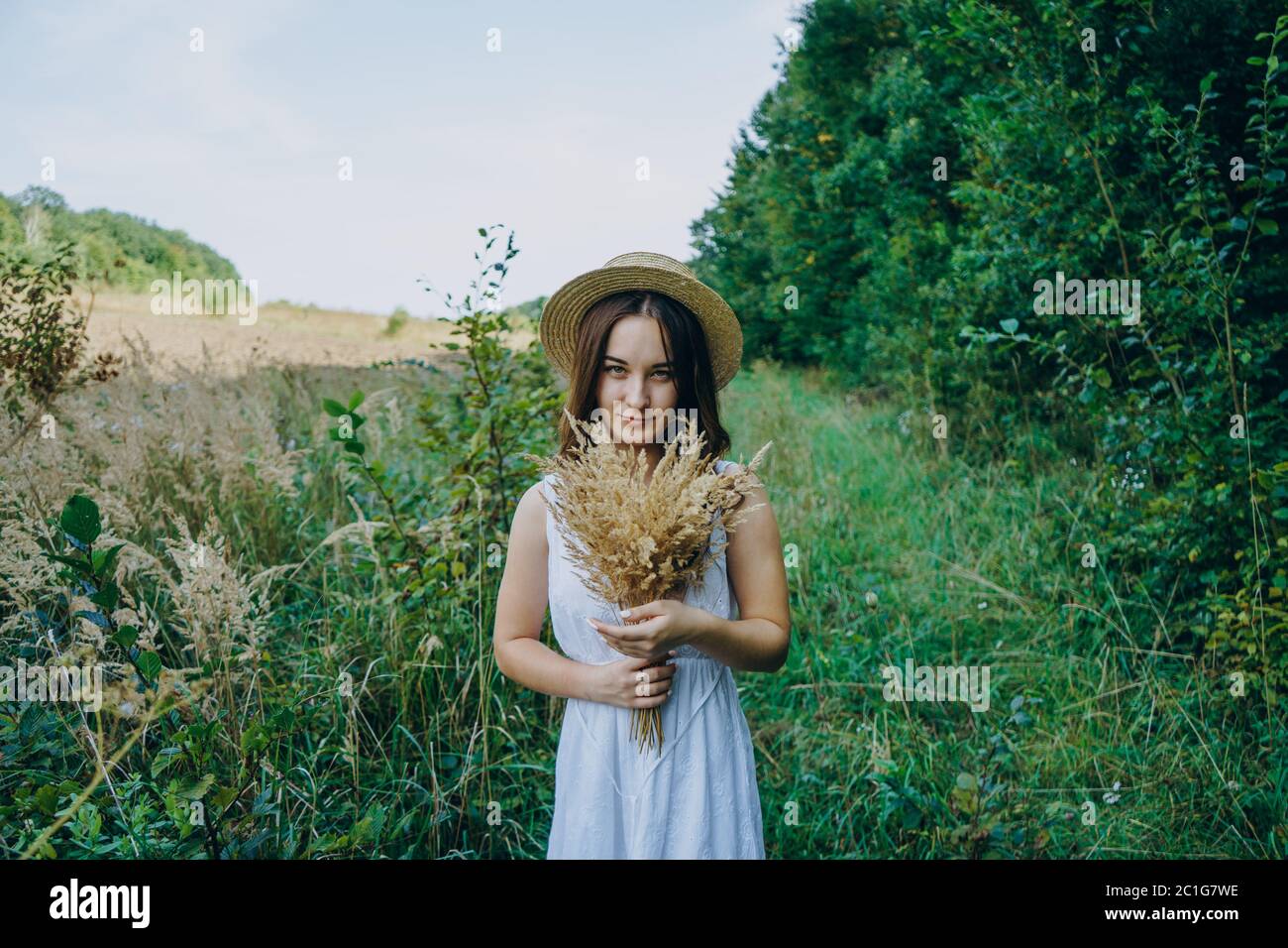 Beautiful girl in a white dress with a bouquet of dried flowers. Young ...