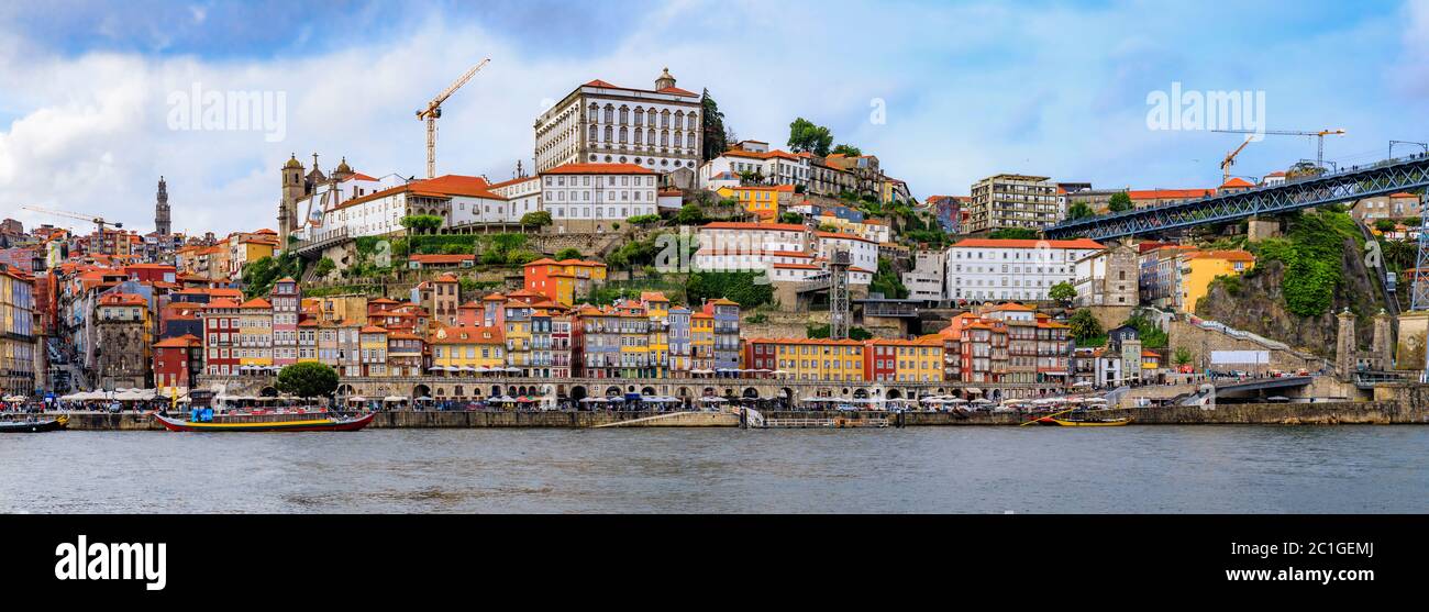 Porto, Portugal - May 30, 2018: Panoramic view onto facades of traditional houses with azulejo tile in Ribeira and tourist rabelo boats across Douro Stock Photo